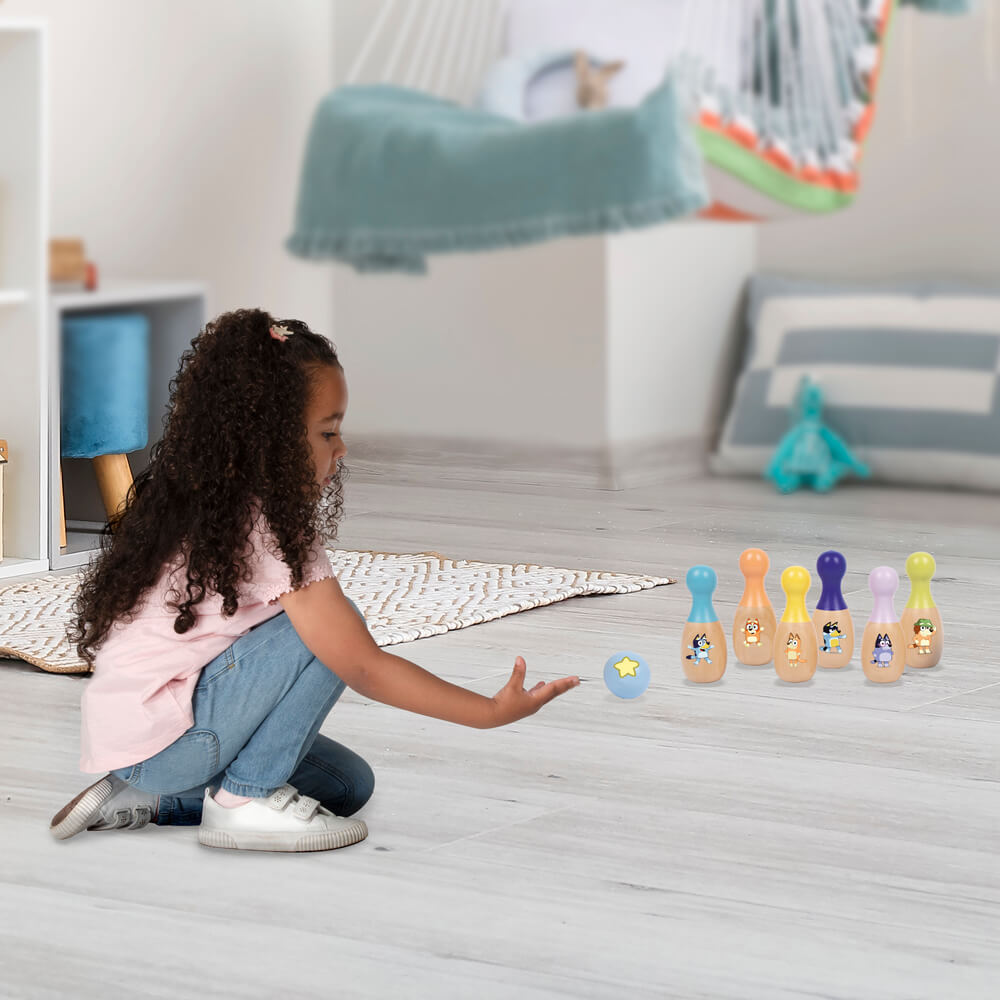 Child bowling with the Bluey Wooden Skittle Set on a rug